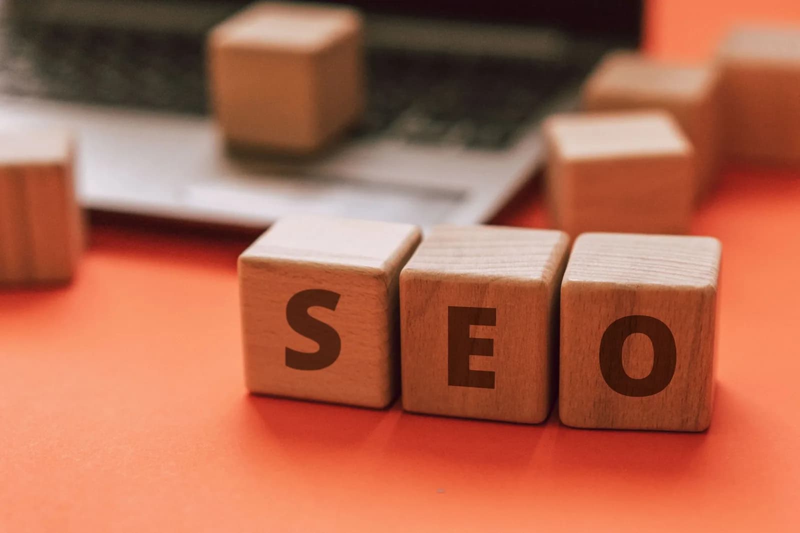 Wooden blocks spelling SEO on a laptop keyboard convey digital marketing concepts.